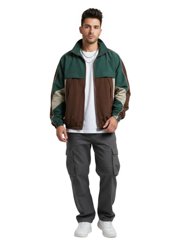 Man wearing a green and brown jacket with gray pants on a white background